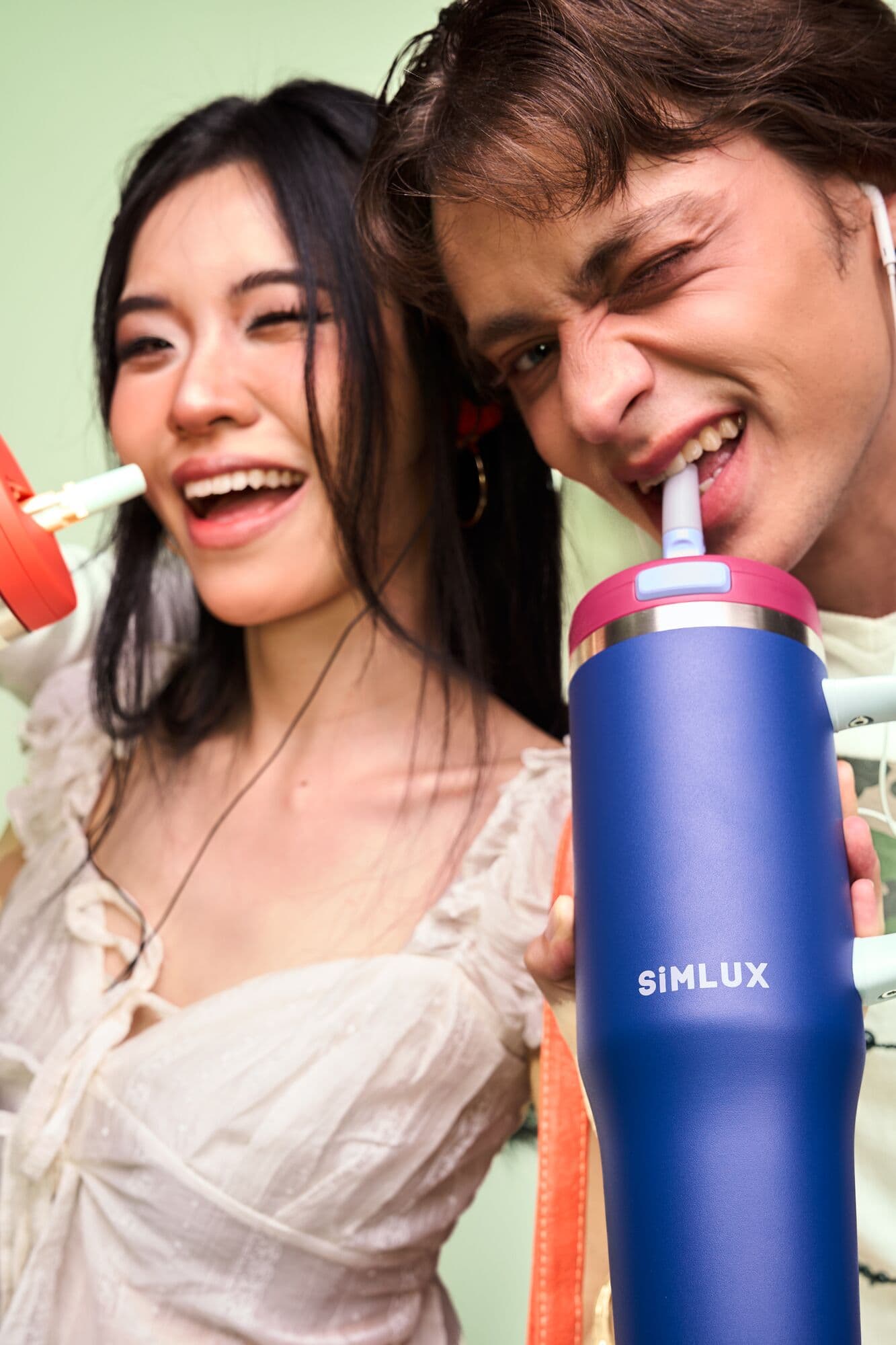 Two models laughing, one drinking from a Deep Blue tumbler
