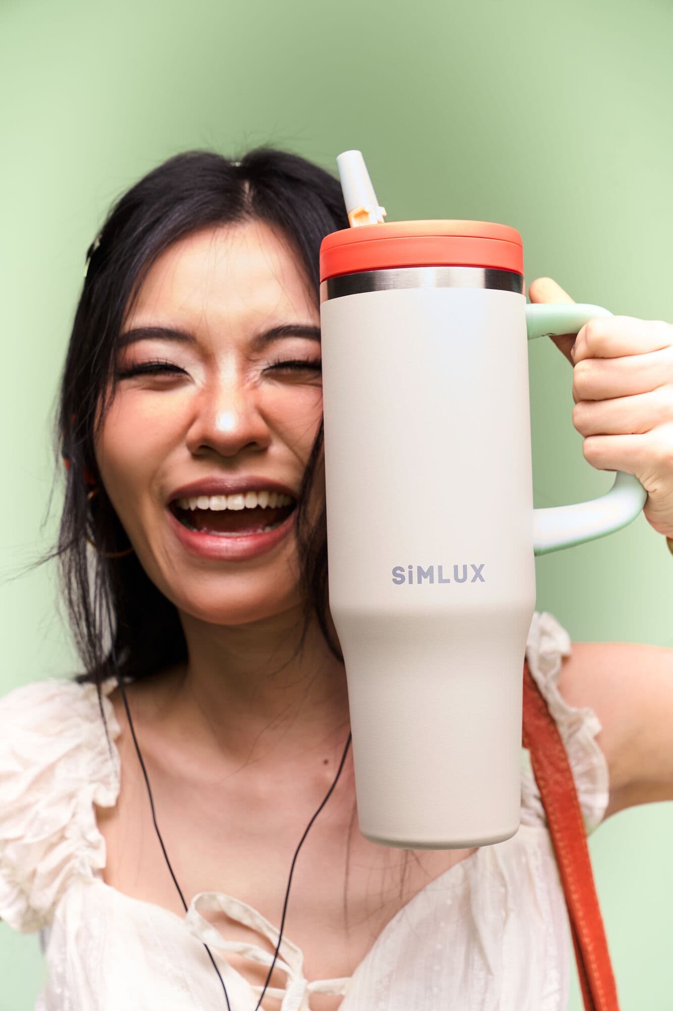 Model laughing, holding a Cream SiMLUX 40oz tumbler to her face
