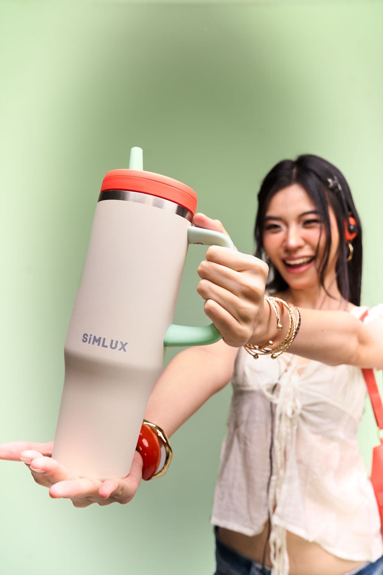 Model holding a Cream tumbler out towards the camera