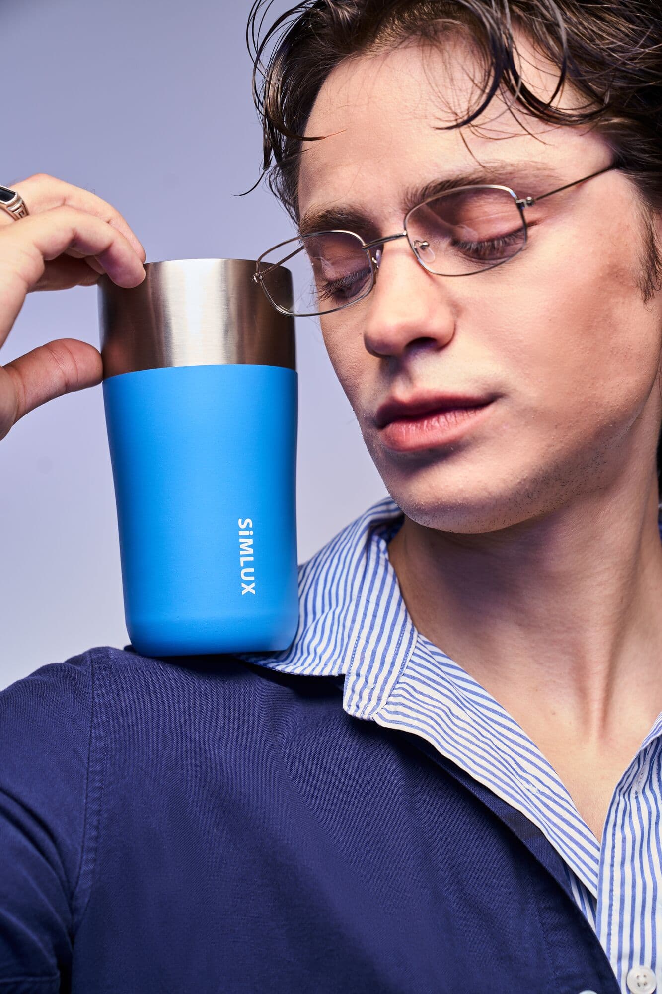 Model resting a blue coffee tumbler on his shoulder