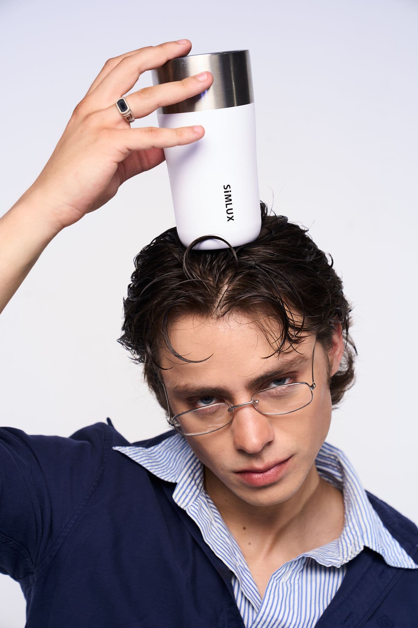 Model balancing a white coffee tumbler on his head
