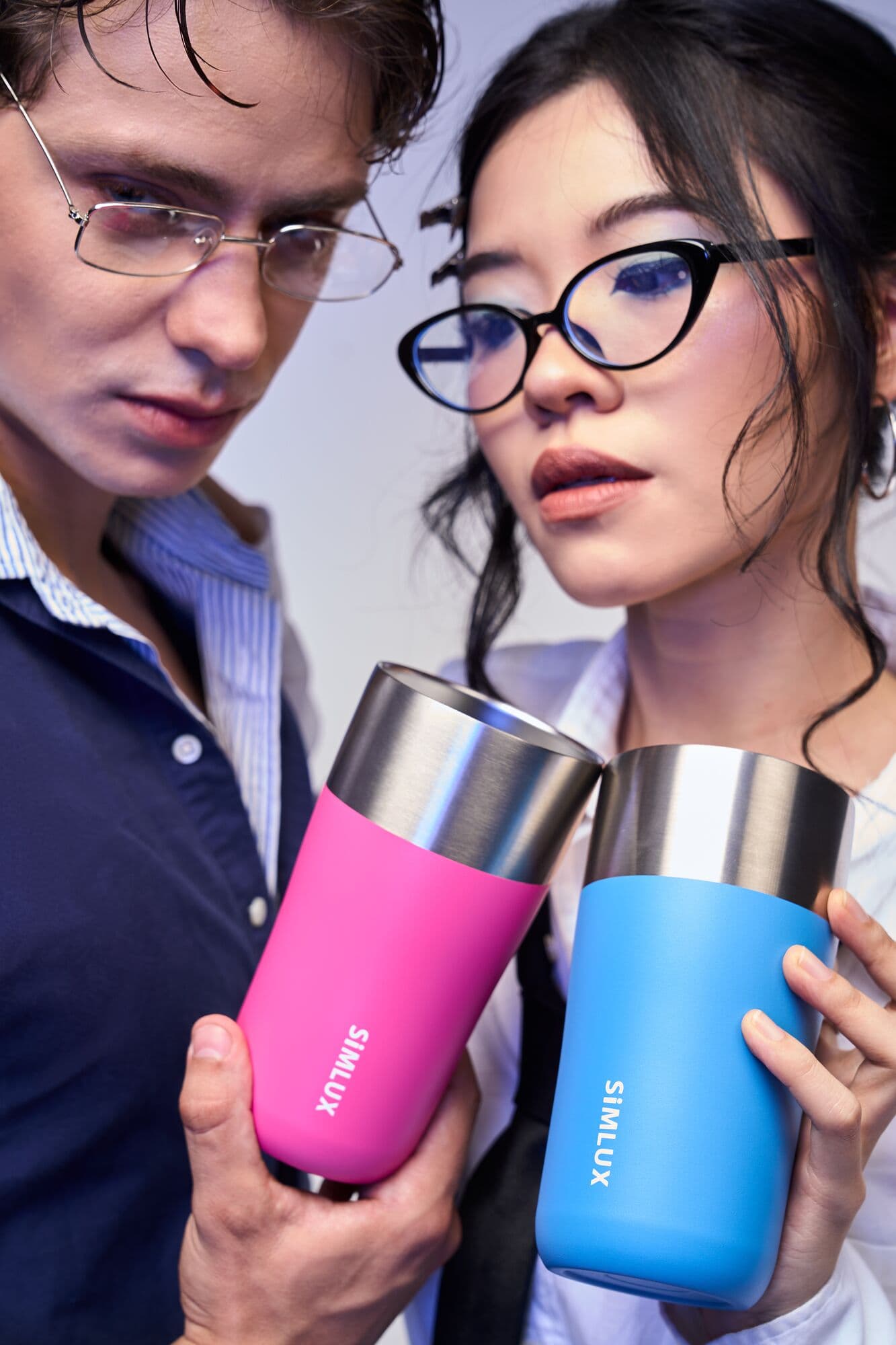 Two models holding pink and blue coffee tumblers
