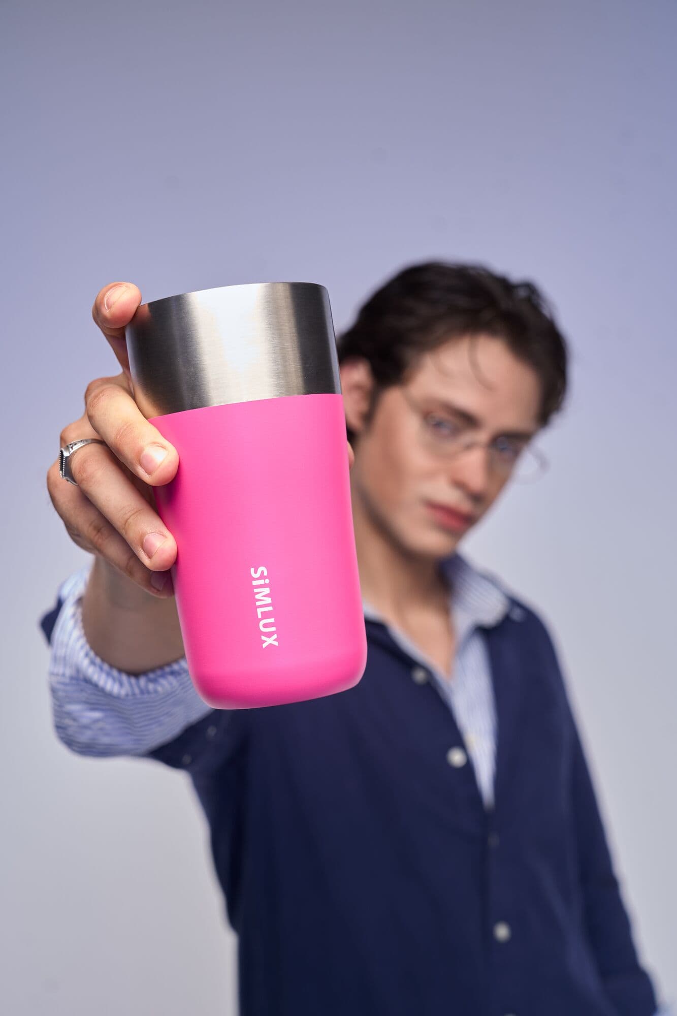 Model holding a pink coffee tumbler towards the camera