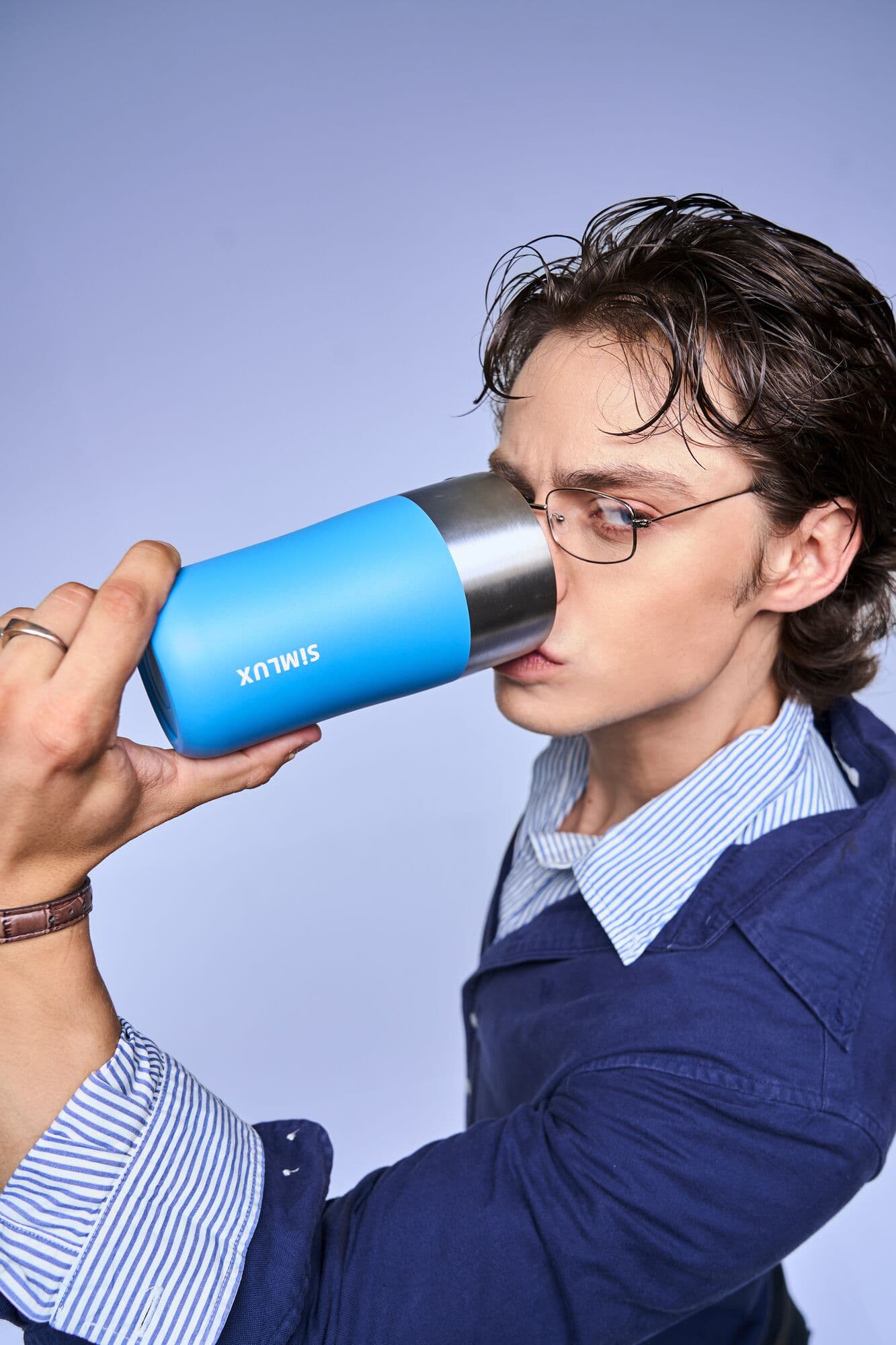 Model drinking from a blue coffee tumbler