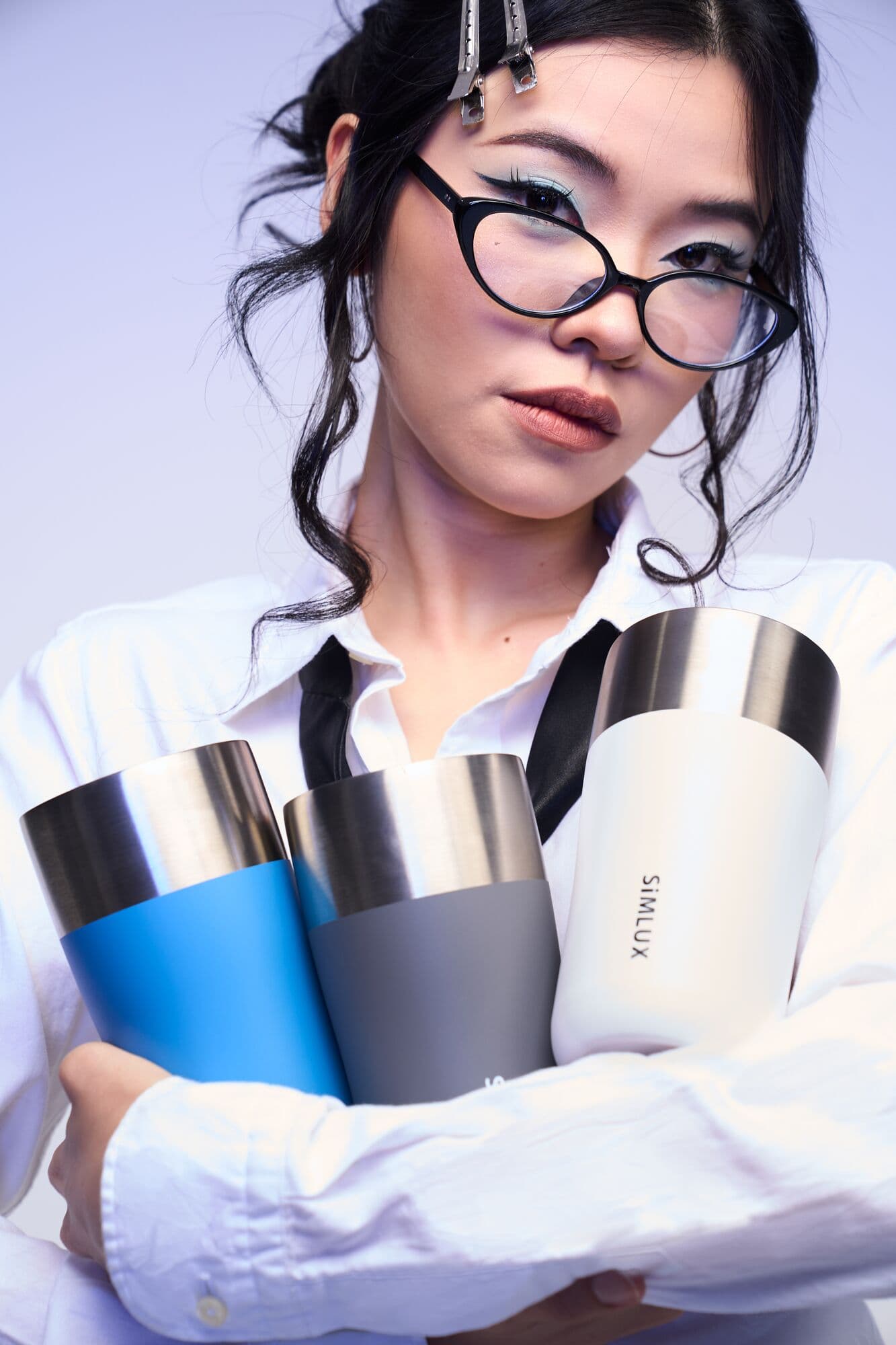 Model hugging SiMLUX coffee tumblers in blue, grey and white